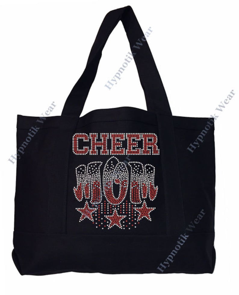 May include: Black canvas tote bag with the words "CHEER MOM" in red rhinestones. The letters are outlined in white rhinestones. There are five red stars with white rhinestone outlines below the words.