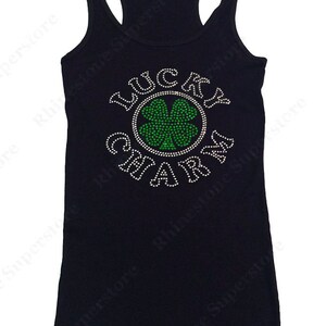 Puede incluir: Camiseta de tirantes negra con un dise&ntilde;o de pedrer&iacute;a que dice "Lucky Charm" con un tr&eacute;bol de cuatro hojas verde en el centro.
