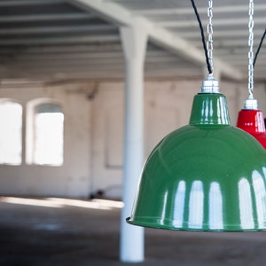 May include: Three industrial pendant lights hanging from the ceiling. The lights are made of metal and have a green, red, and black finish.