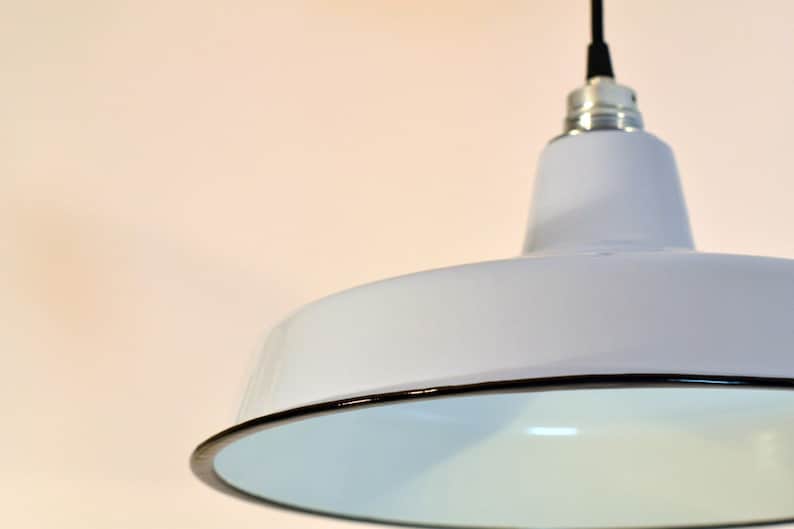 Op de afbeelding: Een witte emaille hanglamp met een zwarte rand. De lamp hangt aan een zwart snoer.
