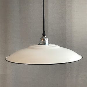 May include: White enamel pendant light fixture with a black cord and a silver socket. The light shade is a wide, flat disc with a black rim.