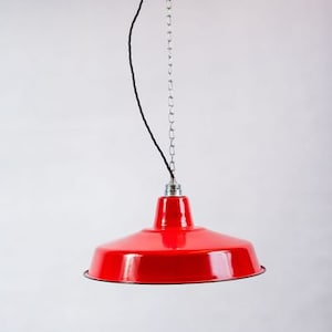 Op de afbeelding: Een rode metalen hanglamp met een ketting die aan het plafond hangt.