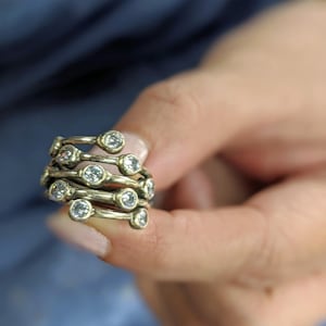 May include: A silver ring with multiple bands and small clear stones. The ring is stacked and has a unique design.