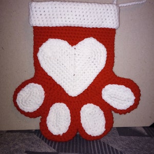 May include: Red and white crocheted stocking shaped like a paw print with a white heart in the center. The stocking has a white crocheted cuff and a white loop for hanging.