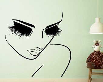 May include: A black and white line drawing of a woman's face with long eyelashes, on a light green wall. A stuffed giraffe sits on a rocking chair in the corner of the room.