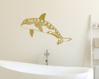 May include: A gold-colored orca whale silhouette wall decal with a patterned design. The decal is shown on a white wall above a white bathtub.