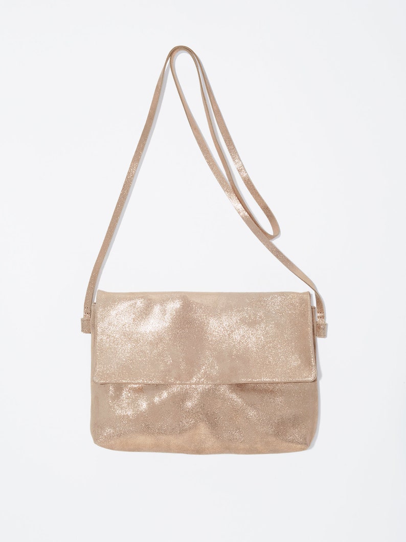 May include: A gold-colored leather crossbody bag with a long strap.