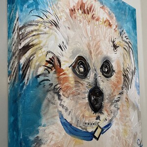 Puede incluir: Una pintura de un perro blanco con pelo marr&oacute;n en la cara y las orejas. El perro lleva un collar azul y mira directamente al espectador. El fondo es de color azul claro.