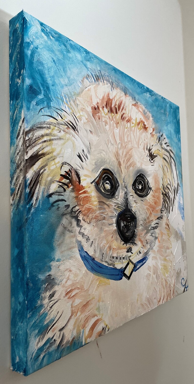 Puede incluir: Una pintura de un perro blanco con pelo marr&oacute;n en la cara y las orejas. El perro lleva un collar azul y mira directamente al espectador. El fondo es de color azul claro.