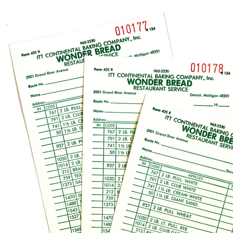 May include: Three vintage Wonder Bread Restaurant Service order forms. The forms are white with black text, including the company name, address, and a list of items with codes and weights. The forms are slightly angled.