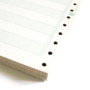May include: A stack of white paper with pale green horizontal lines and a vertical numbered column. The right edge has perforations and a green recycling symbol. The paper is likely for printing or record-keeping.