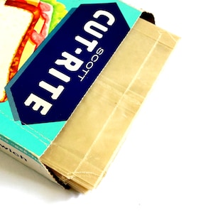 May include: A vintage box of Scott Cut-Rite wax paper. The box is teal with a navy blue and white label that reads "CUT-RITE" and "SCOTT". The wax paper is a light tan colour and is partially visible.