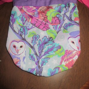 May include: Purple drawstring bag with a white background and a colorful owl print. The owls are pink, purple, and green with white accents. The bag has a purple drawstring and a white background.