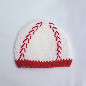 May include: White crocheted baseball hat with red stitching. The hat has a red crocheted brim.