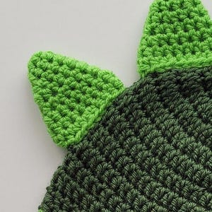 Puede incluir: Sombrero de punto verde y verde oscuro con dos orejas puntiagudas verdes. El sombrero est&aacute; hecho con un punto texturizado.