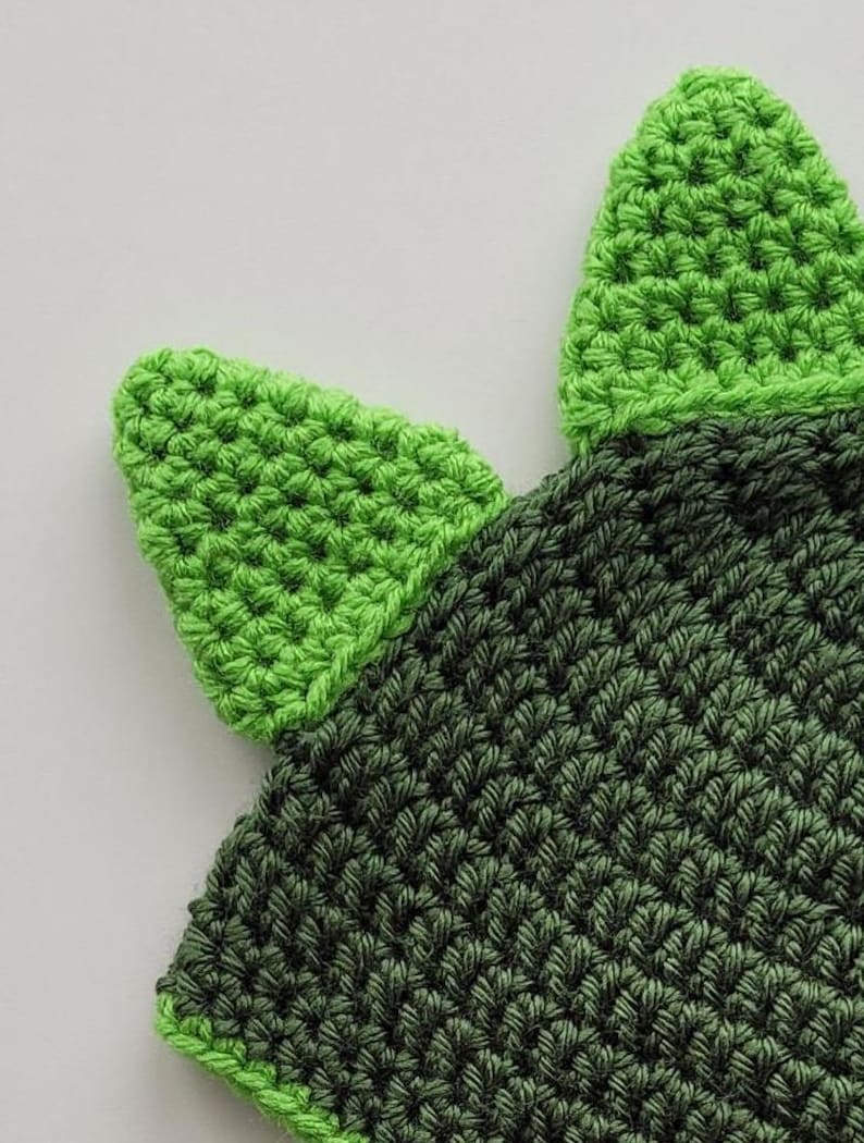 Puede incluir: Sombrero de punto verde y verde oscuro con dos orejas puntiagudas verdes. El sombrero est&aacute; hecho con un punto texturizado.