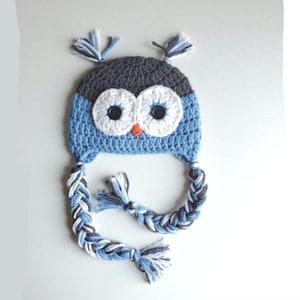 May include: Blue and gray crocheted owl hat with white eyes and a braided cord.