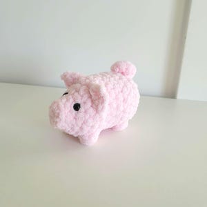 May include: A handmade pink crocheted pig with black eyes and a small tail. The pig is made of soft, fluffy yarn and has a rounded body and small legs. This adorable stuffed animal is a cute gift for kids or a charming home decor item.