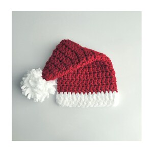 May include: A red and white crocheted Santa hat with a white pom-pom.