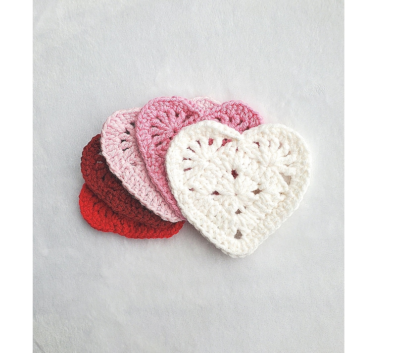 May include: Set of four crocheted heart-shaped coasters in shades of red, pink and white.