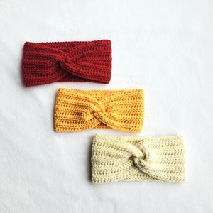 以下が含まれることがあります： 赤、黄色、クリーム色の3つのクロシェ編みヘッドバンド。各ヘッドバンドはねじれた結び目のデザインです。