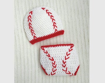 May include: White crocheted baby hat and diaper cover with red stitching, resembling a baseball.