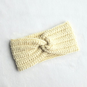 May include: A cream-colored crocheted headband with a knotted design.