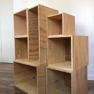 May include: A set of six wooden storage boxes, stacked and arranged in a staggered pattern. The boxes are made of natural wood with a light brown finish. They are all different sizes, with the largest box at the bottom and the smallest box at the top.