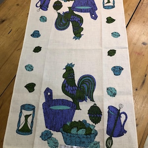 Può includere: Un canovaccio da cucina vintage in lino bianco con un motivo di gallo e utensili da cucina nei toni del verde e del viola. Il canovaccio presenta un cesto di prodotti, una clessidra e la scritta "ALL PURE LINEN".
