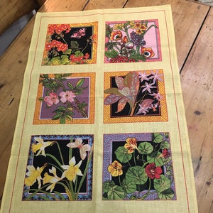 May include: A yellow tea towel with six squares featuring different floral designs. Each square has a black border and a colorful background. The text "Reproduced from the Jackfield Tile Collection, Ironbridge Gorge Museum." is at the bottom of the towel. The text "Linen and Cotton" is in a small white rectangle. The text "Made in UK" and "Richlin RL674" are also on the towel.