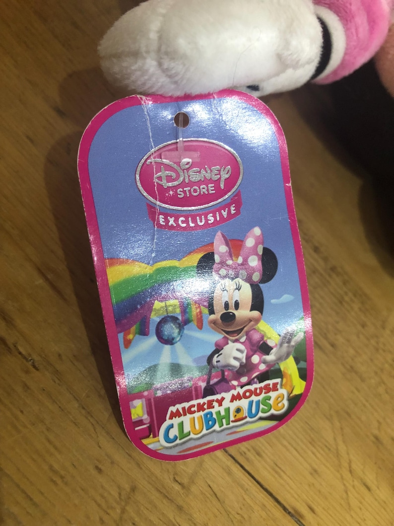 May include: Pink Minnie Mouse plush toy with a Disney Store Exclusive tag. The tag features a rainbow background with Minnie Mouse in a pink and white polka dot dress. The tag also says "Mickey Mouse Clubhouse".