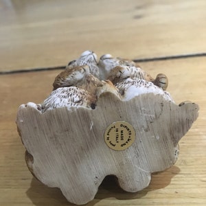 May include: A ceramic figurine of a group of rabbits, painted in shades of brown and white. The figurine is made in Italy and has a gold label on the bottom that reads "Made in Italy, Dipinto a Mano".