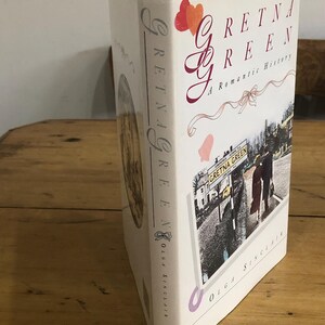 Puede incluir: Un libro de tapa dura titulado "Gretna Green: A Romantic History" de Olga Sinclair. La portada es blanca con detalles en rojo y rosa, incluyendo corazones y un diseño de lazo. El lomo muestra el título verticalmente.