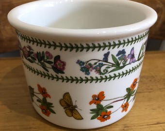 May include: White ceramic planter with a green, brown, and white floral pattern. The planter features a variety of flowers, butterflies, and leaves.
