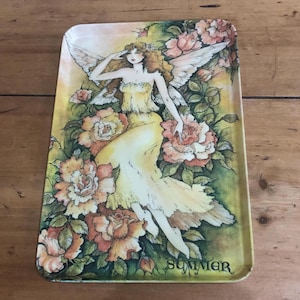 Pode incluir: Bandeja retangular com um desenho de fada. A fada está vestida com um vestido amarelo e tem asas brancas, rodeada por rosas cor-de-rosa e laranja. A palavra "Summer" está impressa na bandeja.