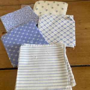 Pode incluir: Uma coleção de quadrados de tecido com vários padrões em azul e branco. O conjunto inclui peças com estampas florais azuis, um padrão de grade azul e branco, um pequeno motivo de estrela azul e um design de listras horizontais.