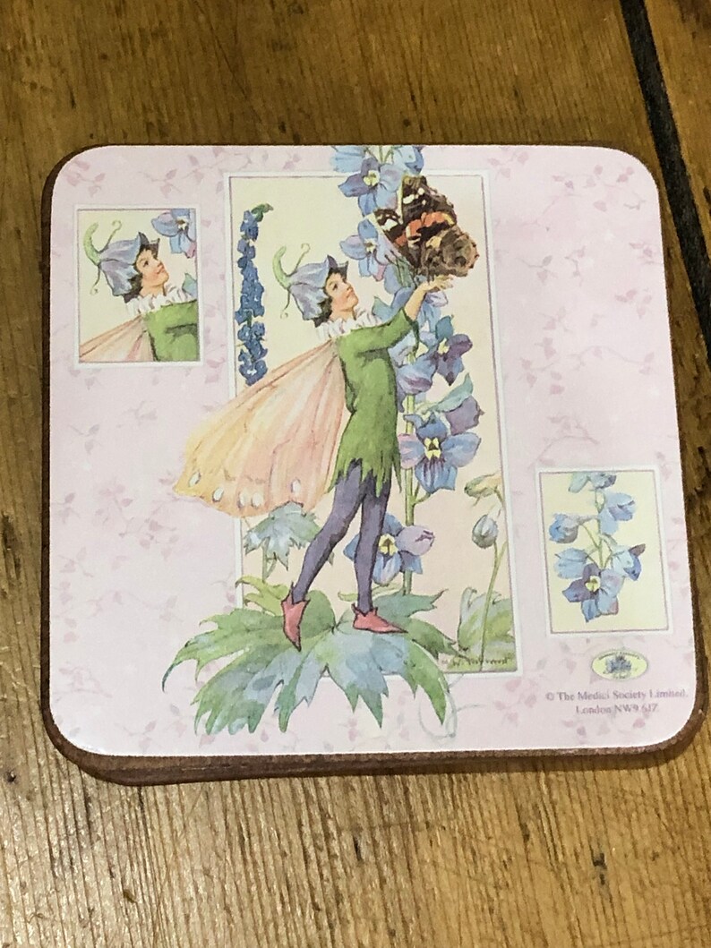 May include: A pink and white coaster with a fairy illustration. The fairy is wearing a green dress and has wings. The fairy is holding a butterfly with black and orange wings. The coaster has a floral design and the text "The Medici Society Limited, London NW9 6JZ" in the bottom right corner.