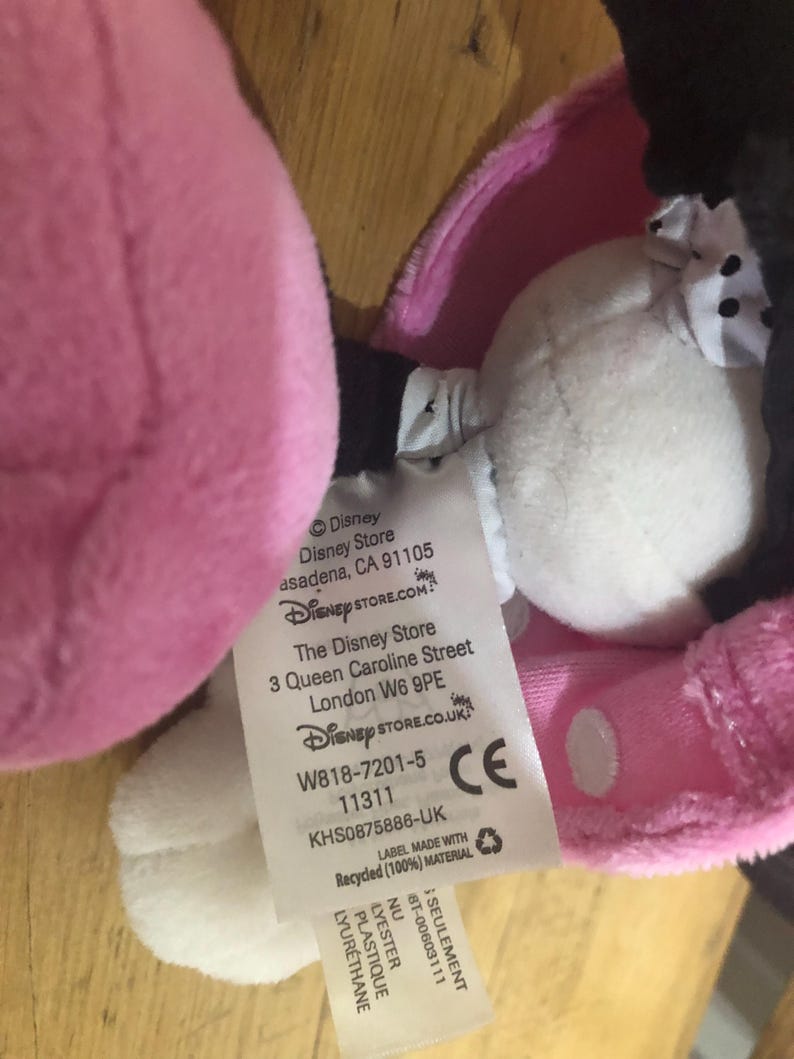 May include: Pink and black plush toy with a white tag attached. The tag has the Disney Store logo and information about the store's location and website. The tag also includes the product number, W818-7201-5, and the CE mark.