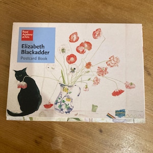 May include: A rectangular postcard book featuring a print of a black cat sitting next to a white pitcher filled with red and pink poppies. The cover includes a blue square with the text Royal Academy of Arts, Elizabeth Blackadder, Postcard Book.