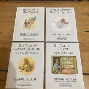 May include: Four Beatrix Potter children's books are shown, including "The Story of Miss Moppet" and "Appley Dapply's Nursery Rhymes." The books have white covers with illustrations and text. The publisher is F. Warne & Co. The books are new colour reproductions.