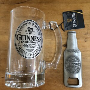 May include: A clear glass beer mug with a silver Guinness logo and a silver bottle opener with a Guinness logo. The bottle opener is shaped like a beer bottle.