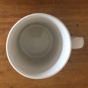 Puede incluir: Una taza de cer&aacute;mica blanca con asa. La taza est&aacute; vac&iacute;a y tiene un acabado liso y brillante.