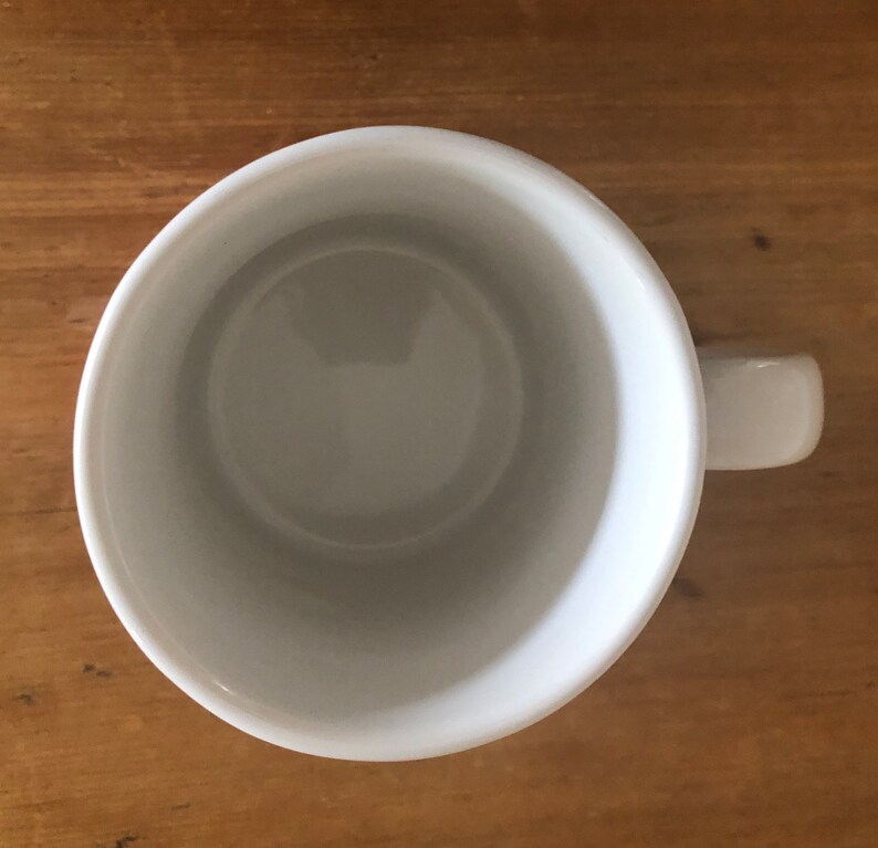 Puede incluir: Una taza de cer&aacute;mica blanca con asa. La taza est&aacute; vac&iacute;a y tiene un acabado liso y brillante.