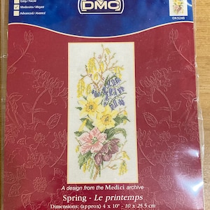 May include: A cross-stitch kit with a floral design in yellow, pink, and purple. The kit includes the DMC logo and the text "Spring - Le printemps". The dimensions are approximately 10 x 25.5 cm.