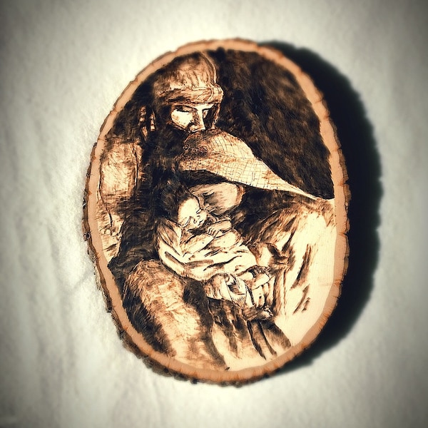 Handmade Wood Burning of the Holy Family. Joseph kisses the head of Mary as she gazes at the Christ Child