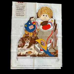 May include: A vintage fabric panel featuring a cartoon illustration of a young person in a football uniform holding a football, with a dog and a pennant. The panel includes instructions and the text "Leave Open For Stuffing".