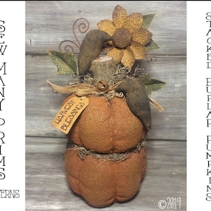 May include: Stacked burlap pumpkins with a sunflower and a sign that says "Harvest Blessings".