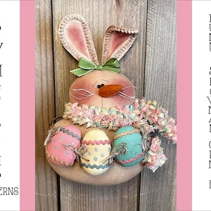 May include: A handmade bunny snowman ornament with pink ears, a green bow, and a carrot nose. The bunny is holding three pastel-colored Easter eggs.