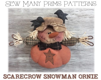 May include: A handmade scarecrow snowman ornament with a pumpkin body, a plaid shirt, a straw hat with black birds, and a brown bow tie. The ornament is made of fabric and has a rustic, vintage look.  The text "SEW MANY PRIMS PATTERNS" is at the top of the image and the text "SCARECROW SNOWMAN ORNIE" is at the bottom of the image.