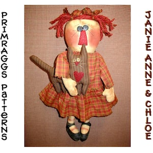 May include: A handmade rag doll with red hair and a plaid dress, holding a brown and white cat with a red heart on its chest. The doll is standing on a red and white checkered background. The text "PRIMRAGGS Patterns" is on the left side of the image and "JANIE ANNE & CHLOE" is on the right side of the image.